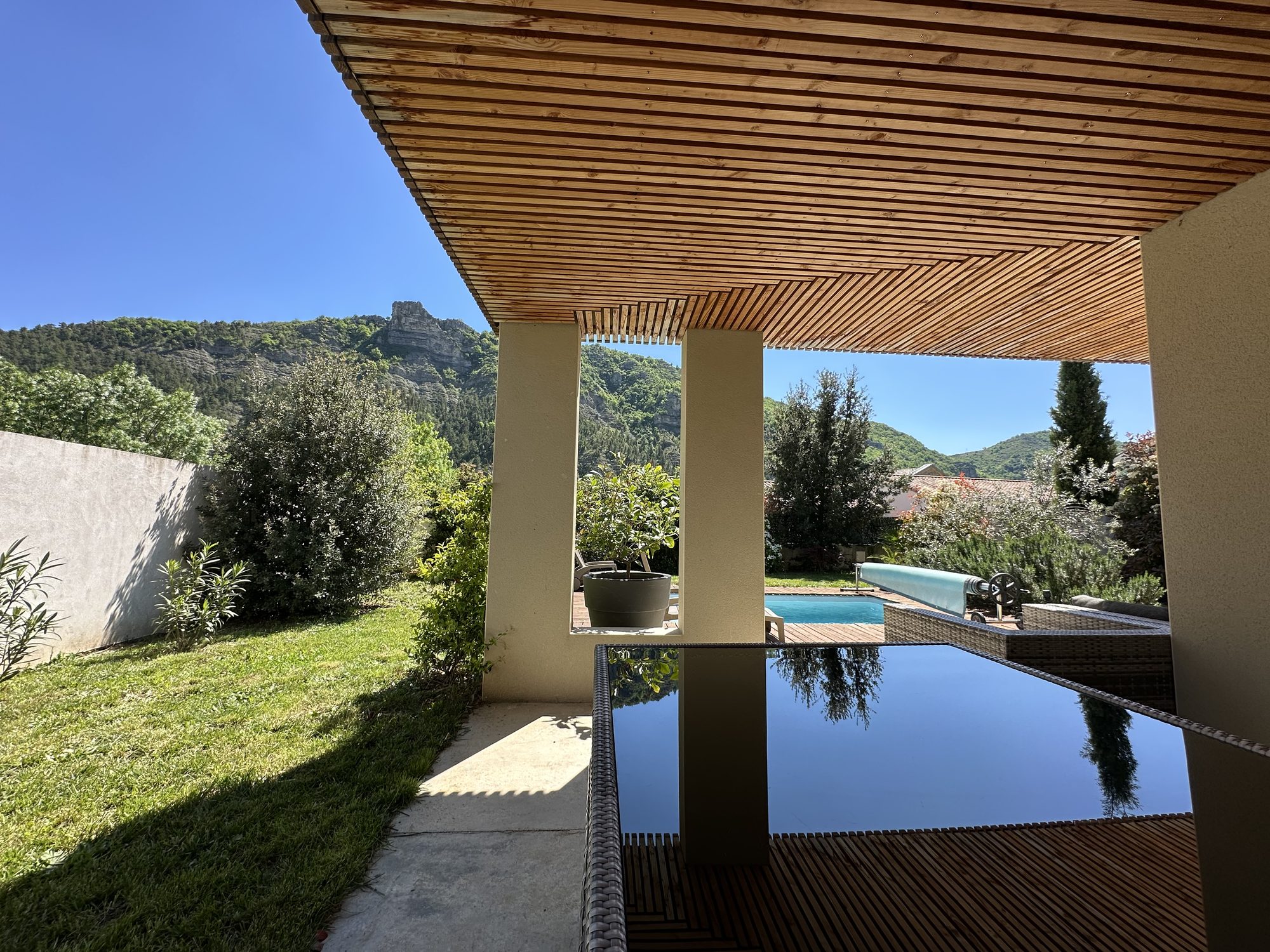 Vue depuis la pergola sur la piscine, le jardin et les falaises